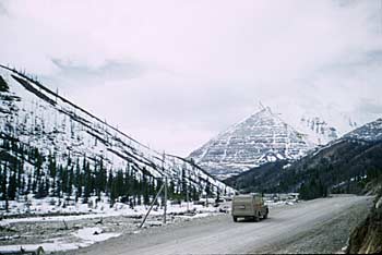 Car traveling the Alaska Highway beside Tetsa River near Summit Pass, Mile 390. 1948.
