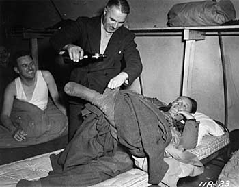 Pouring beer down his leg in the barracks. ca. 1944. 