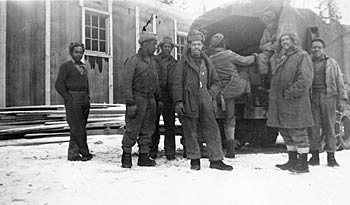 A group of black men behind and boarding truck in winter. ca. 1942