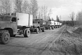 Convoy of army trucks carrying construction material.